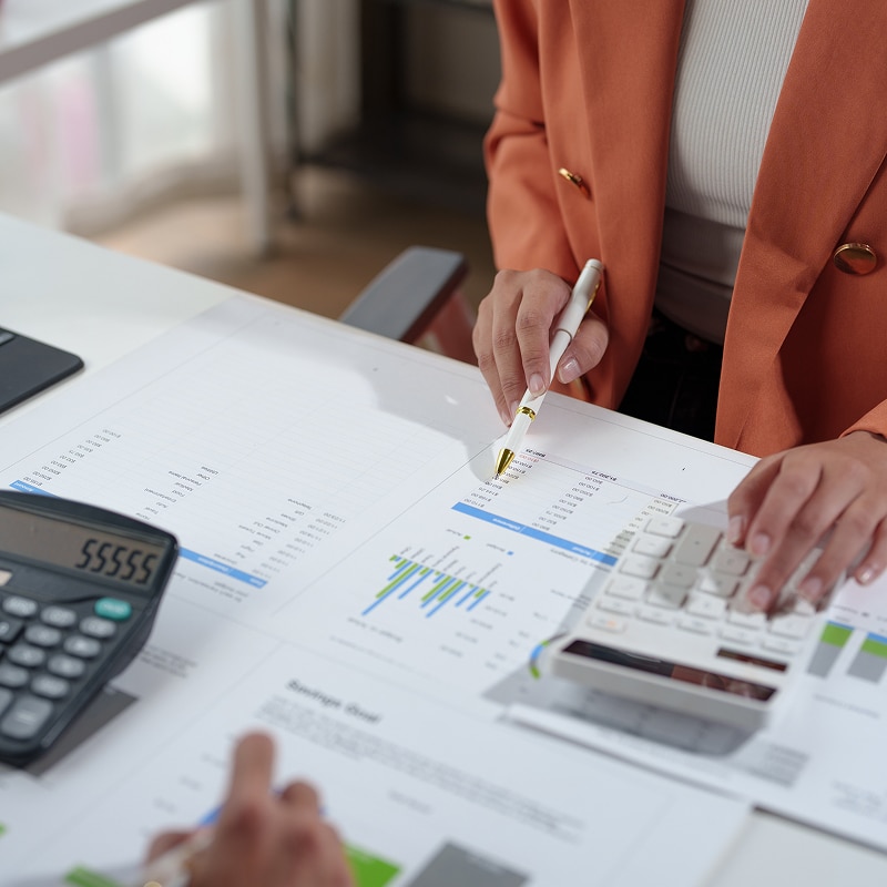 Analyse financière : Calculer et vérifier votre budget d'entreprise. Mains analysant des documents de budget et des graphiques financiers. Utilisation d'une calculatrice pour vérifier les chiffres de comptabilité.